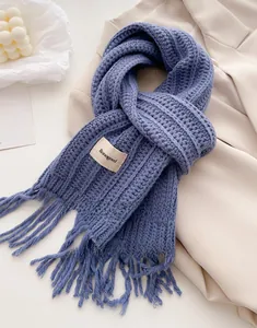 Detailed close-up of blue knitted wool scarf with tassel fringe and brand label
