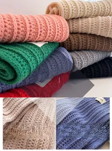 Detailed close-up of thick cable knit texture and tassels on colorful wool scarves