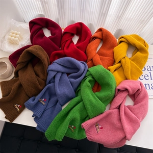 Multiple colors of knit scarves with dog embroidery on a minimalist styled background