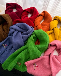 Detail of colorful knitted scarves with puppy embroidery and polka dot patterns