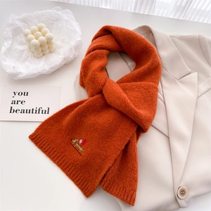 Detail of warm orange knitted scarf with embroidery of dachshund holding colorful balloons