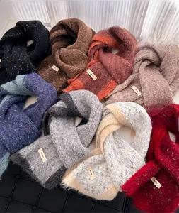 Detailed macro view of multiple colorful knitted scarves with minimalist woven labels