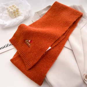 Detail of orange knitted scarf with embroidery of a dachshund holding a balloon