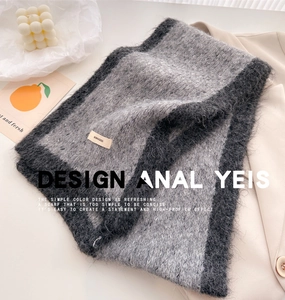 Detail of the gray knit scarf texture with a brand label and fluffy wool-like finish