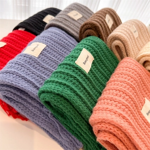 Detailed close-up of textured cable knit wool scarves with tassels in various vibrant colors