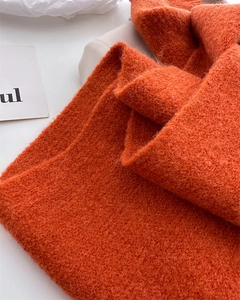 Close-up of thick orange knit scarf showing fuzzy mohair texture and warm wool fabric