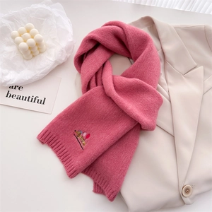 Close-up of pink knitted scarf with puppy embroidery on beige blazer outfit