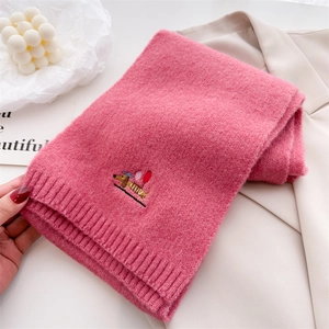 Close-up of pink knit scarf with embroidered dachshund wearing a hat and balloon