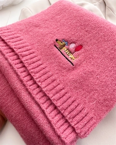 Detailed close-up of a pink knitted scarf featuring a cute dachshund embroidery with balloons