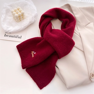Detail of red knit scarf with embroidered puppy pattern on a beige blazer background