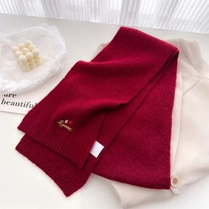 Detail of burgundy knit scarf featuring embroidered dachshund dog and ribbed edges