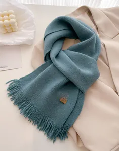 Macro detail of a grey-blue knitted scarf with tassels and a leather handmade tag