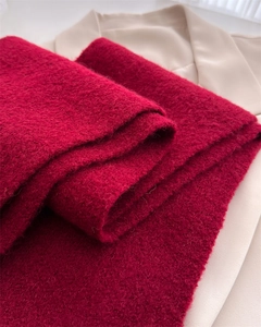 Macro texture of a thick red knitted wool scarf showing soft fiber detail and quality