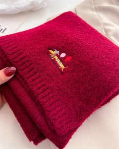 Detailed texture of red knitted scarf featuring a cute dachshund embroidery and soft wool