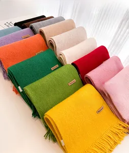 Detailed view of colorful knit scarves featuring fringe edges and handmade leather labels