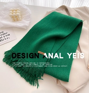 Detail of green knitted scarf with handmade leather label and fringe tassels