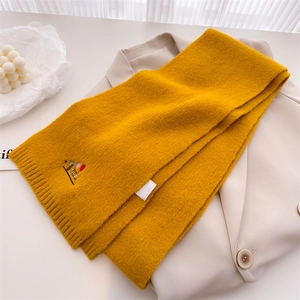 Detail of ginger yellow knitted scarf with small animal embroidery and soft texture
