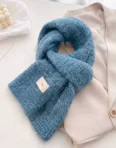Detailed knit texture of blue wool scarf with tag on a beige blazer background