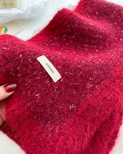 Close-up of red knit wool scarf texture with a woven BONOGEED brand label detail