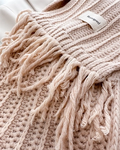 Close-up of pink knitted wool scarf featuring vertical textures and elegant long tassels