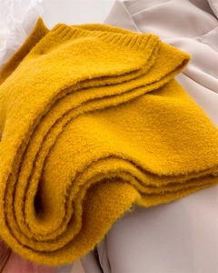 Detailed close-up of ginger yellow knit scarf showing soft ribbed edges and fuzzy texture