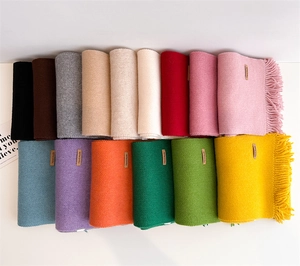 Flat lay of colorful knitted scarves with tassels and handmade label in 15 vibrant colors