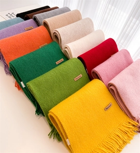 Macro shot of knitted scarves in various colors with handmade leather label and fringe detail