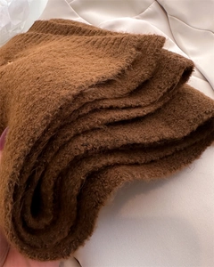 Close-up of thick brown bouclé knit texture on a winter scarf with soft plush finish