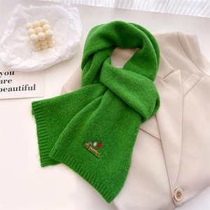 Green knit scarf with embroidered dachshund puppy dog and balloon on warm neutral background