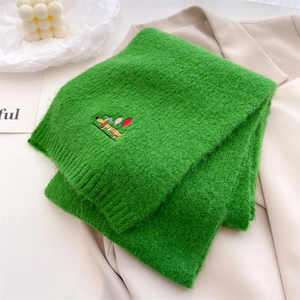 Close-up of green knit scarf featuring a cute dachshund embroidery and soft texture