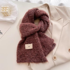 Detail of burgundy wool knit scarf with white speckled texture on a beige blazer