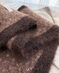 Detailed close-up of fluffy brown knit scarf texture showing soft wool blend fabric