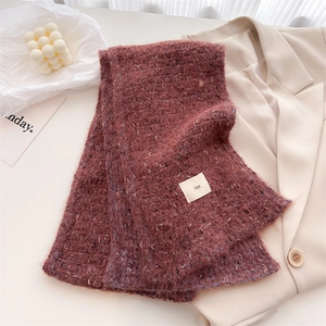 Macro detail of dark red knit wool scarf texture with ins label on beige blazer