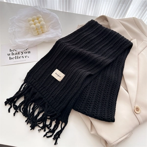 Detail of black knit wool scarf with vertical ribbed texture and tassel fringe edge