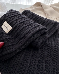 Detailed close-up of thick black ribbed knit wool scarf with a woven brand tag