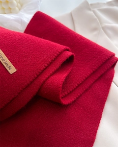 Detail of red knitted wool scarf with high-quality handmade leather label and soft texture