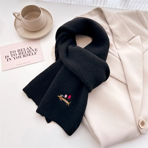 Close-up of black knitted scarf featuring delicate puppy embroidery on wool blend fabric