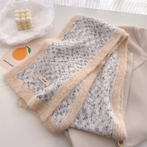 Detail of knit wool scarf with letter brand label and plush beige decorative edging