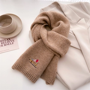 Close-up of camel knit scarf with detailed dachshund embroidery on a white blazer