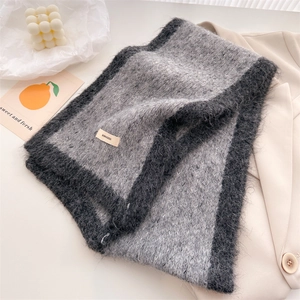 Close-up of fluffy grey and black knit scarf with brand label on beige blazer