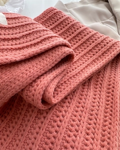 Close-up of thick coral pink wool knit scarf showing ribbed texture and fringe detail