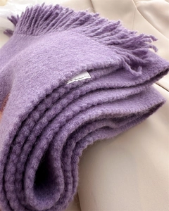 Detail of purple knitted scarf with thick fringe and texture showing the brand label
