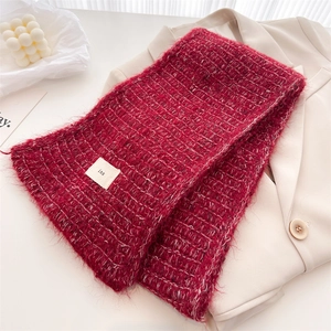 Detail of dark red knit wool scarf with soft fluffy texture and white woven tag