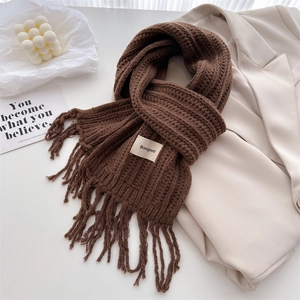 Detail of dark brown knitted wool scarf with tassel fringe and white brand label