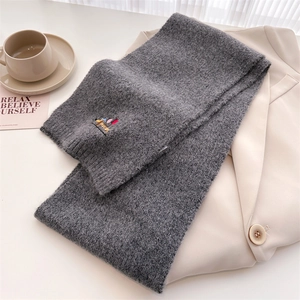 Detailed knit texture of a dark grey winter scarf with colorful puppy embroidery