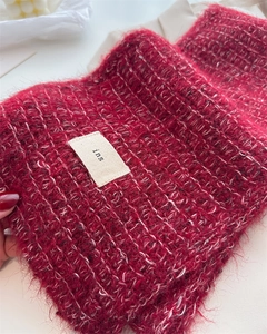 Macro detail of dark red mohair wool knit scarf showing fluffy texture and woven ins label