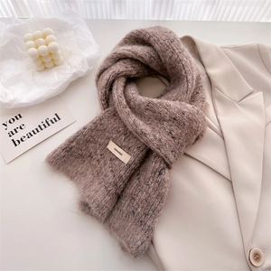 Detail of soft wool knit scarf with BONOGEED brand label on elegant warm beige fabric
