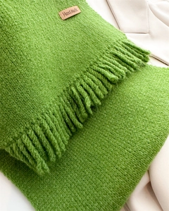 Detailed macro view of bright green knit scarf texture with fringe and Hand Made leather tag