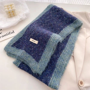 Close-up of teal knit wool scarf featuring BONDGEED letter label and fuzzy texture