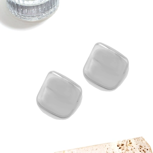 Détail macro de boucles d'oreilles carrées en argent sur une surface en pierre